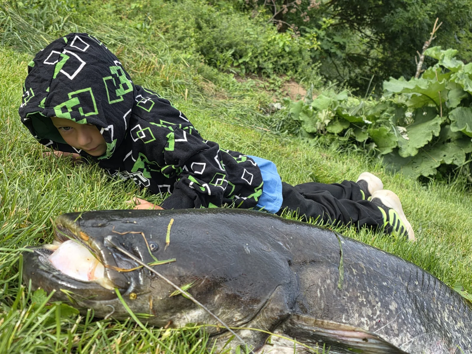 Kind neben einem Fisch auf der Wiese am Neckarufer