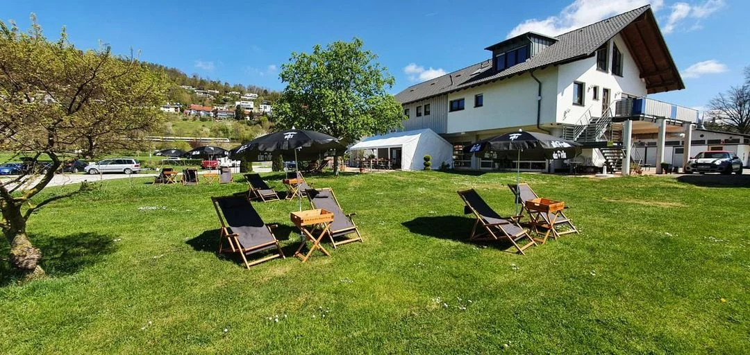 Liegestühle auf der Wiese vor dem weißen Gebäude von Marta's Bistro unter blauem Himmel
