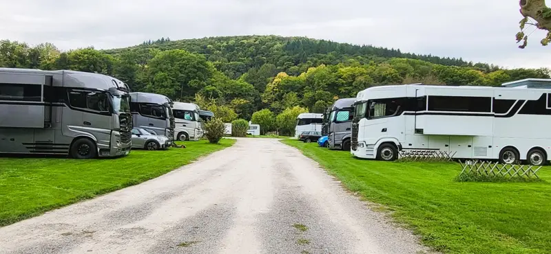 Wohnmobile auf Rasenflächen beiderseits eines geschotterten Wegs