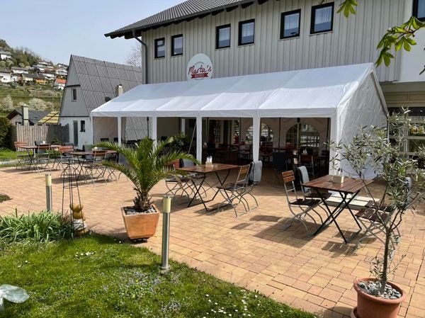 Terrasse von Marta's Bistro mit Tischen und Stühlen vor dem Bistrogebäude